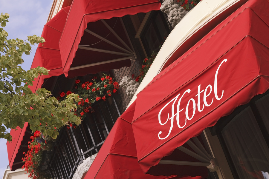 Red storefront awnings with custom printed lettering on a hotel entrance