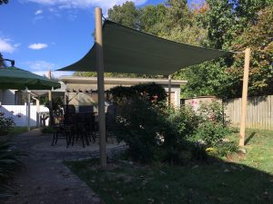 Freestanding fabric canopy over a backyard seating area with landscaping