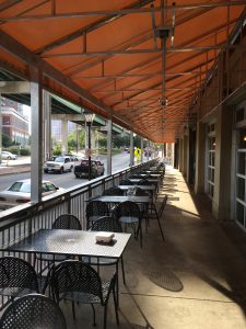 Commercial patio cover shading a long outdoor porch with tables and chairs