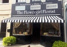 Stylish black-and-white striped fabric awning over charcoal-color facade of florist shop