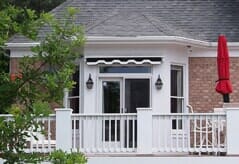 Scalloped-edge black and white awning retracted over patio door of a luxury home