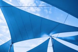 Awnings in sails shape over cloudy sky background.