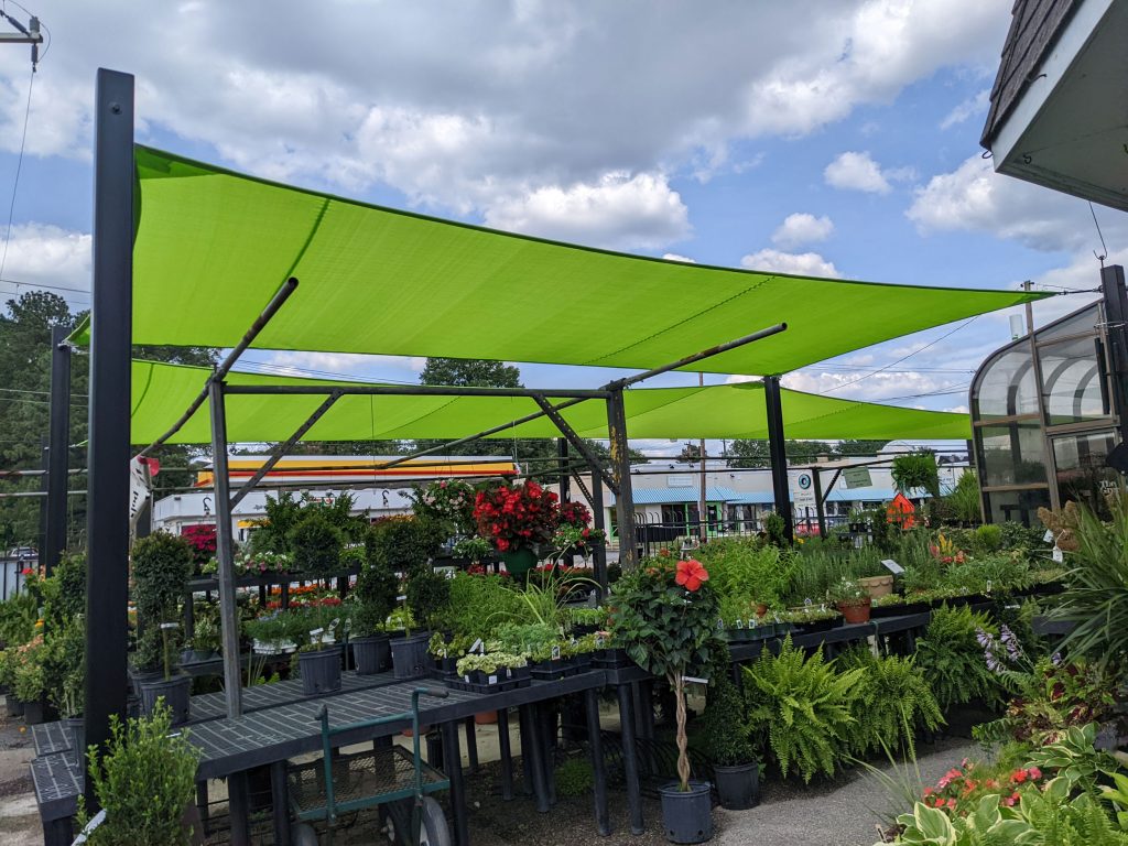 Tensioned shade sail covering an outdoor garden center display area